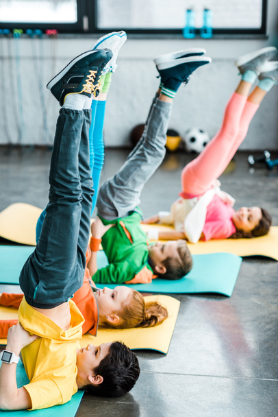 Kids doing candlestick exercise on mats in gym - Foto, Bild