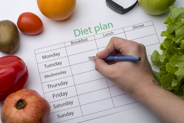 The doctor writes a prescription to the patient, makes a diet plan in the workplace with fresh fruit. Top view, the concept of healthy eating. - Photo, Image