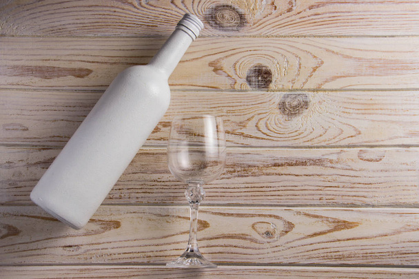 Белая матовая бутылка красного вина с бокалом на светлом деревянном фоне
 - Фото, изображение