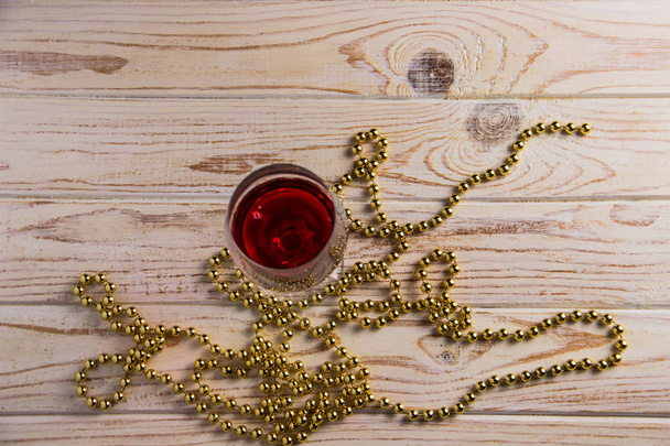 Un bicchiere di vino rosso su uno sfondo di legno con perline dorate per l'arredamento
 - Foto, immagini