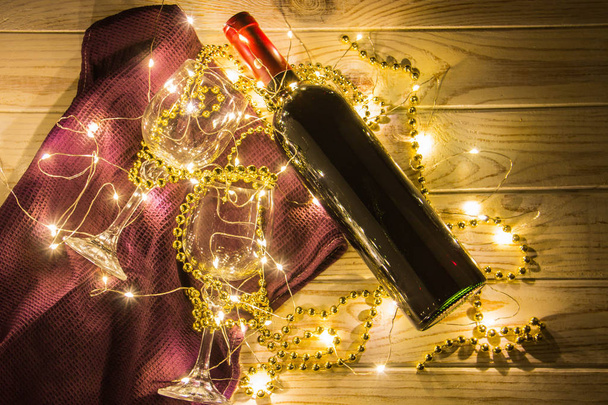Un bicchiere di vino rosso su uno sfondo di legno con l'arredamento a forma di perline d'oro e luci gialle
 - Foto, immagini