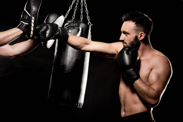 svalnatý boxer bojovat s mužem v děrování rukavice izolované na černém - Fotografie, Obrázek