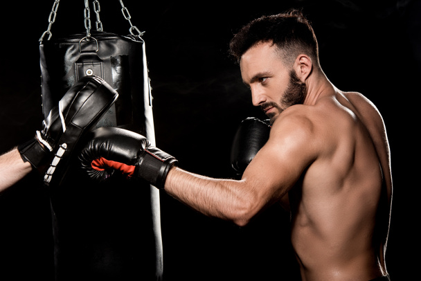 athletic boxer fighting with man in punching gloves isolated on black - Fotoğraf, Görsel