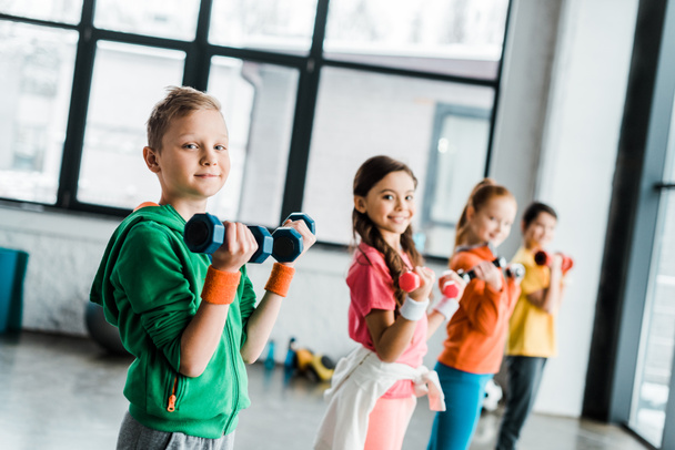 Cute children with dumbbells looking at camera - Foto, immagini