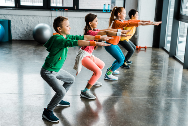 Group of kids doing squats in gym - Valokuva, kuva