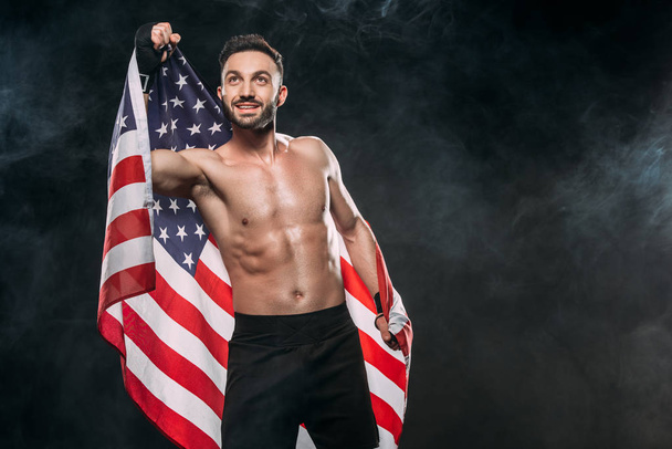 happy athlete holding american flag on black with smoke - Foto, Imagen