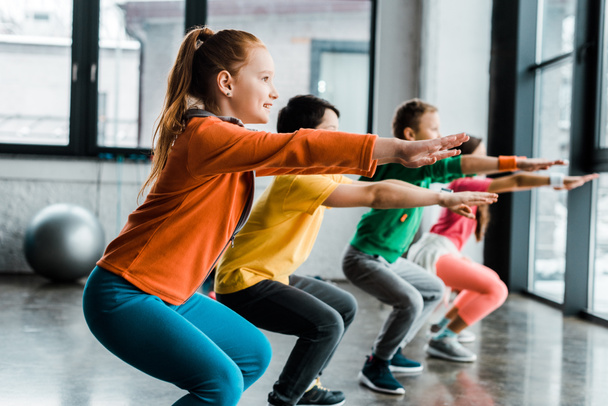 Enfants concentrés faisant des squats pendant l'entraînement en salle de gym
 - Photo, image