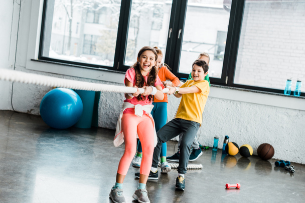 Enfants excités jouant remorqueur de guerre dans la salle de gym
 - Photo, image