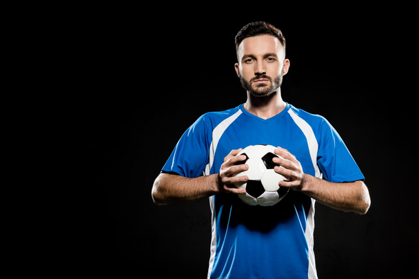 футболіст тримає м'яч в руках ізольовано на чорному
 - Фото, зображення