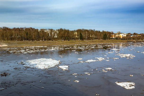Ice drifting on the river in the city. Spring ice melts and floats along the river. - Zdjęcie, obraz