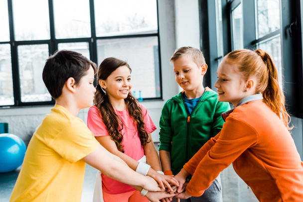 Group of happy kids holding hands in gym - Фото, изображение