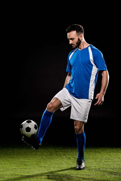 bearded man playing with ball on grass isolated on black - Photo, Image