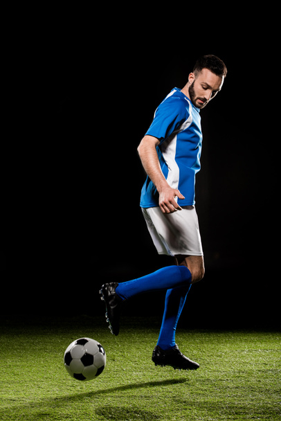 muscular sportsman in uniform playing with ball isolated on black - Zdjęcie, obraz