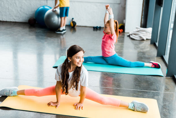 Cute kids doing twine on fitness mats in gym - Fotografie, Obrázek