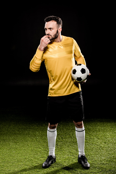 handsome bearded coach blowing whistle while holding ball isolated on black - Φωτογραφία, εικόνα