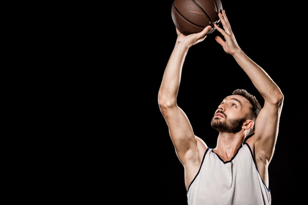 handsome basketball player throwing ball isolated on black - Photo, Image