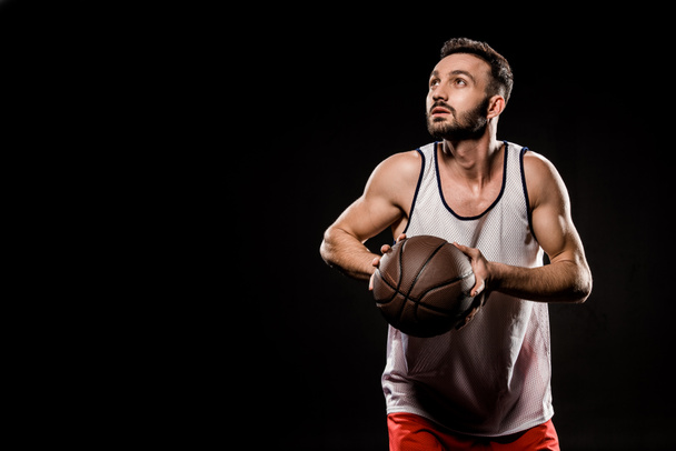 handsome basketball player holding ball isolated on black - Photo, Image