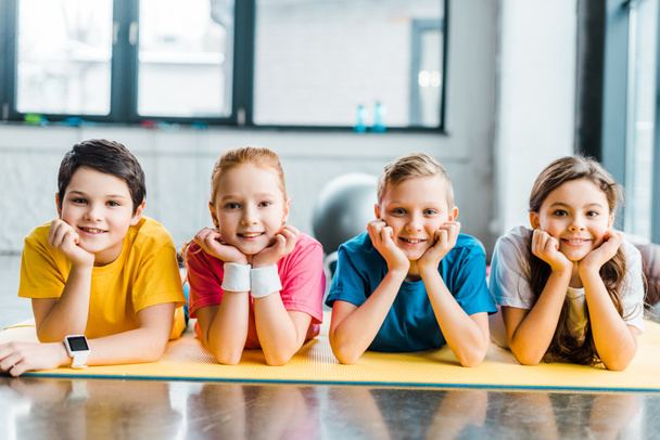 Cute preteen kids lying on fitness mat and looking at camera - Photo, Image