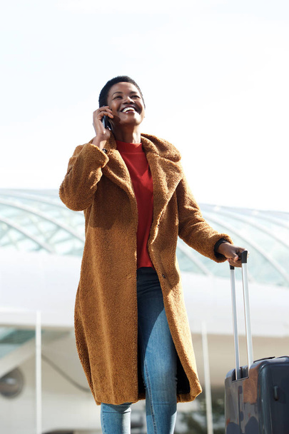 Портрет щасливої молодої жінки, що подорожує з валізою та мобільним телефоном
 - Фото, зображення