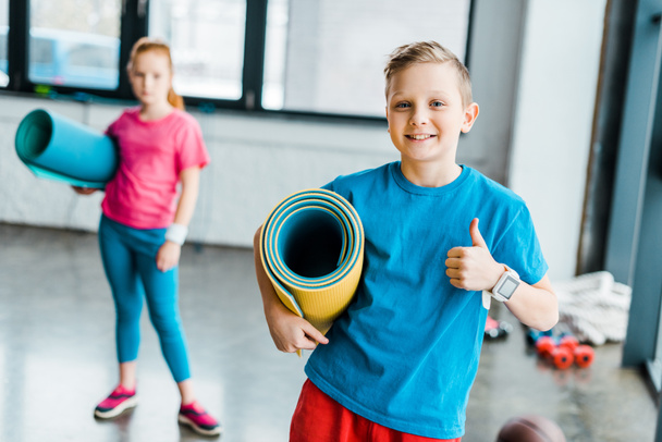 Boy holding fitness mat and showing thumb up - Photo, Image