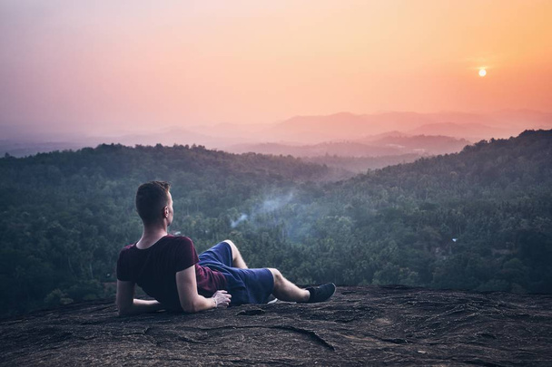Young man contemplation on top of rock. Landscape at sunset in Sri Lanka. - Photo, Image
