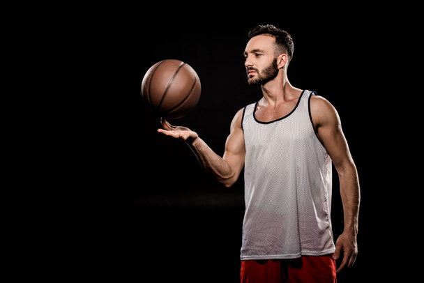 bel giocatore di pallacanestro che gira palla sul dito isolato sul nero
 - Foto, immagini