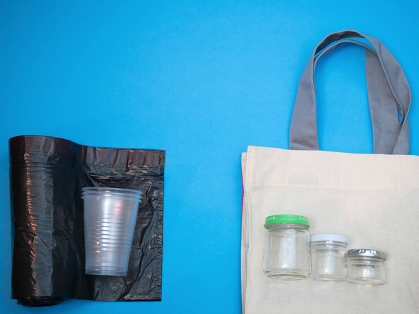 concept de matériaux artificiels vs naturels. des gobelets en plastique sur des sacs poubelle contre des bocaux en verre et des sacs en lin. réutilisation des récipients alimentaires
 - Photo, image