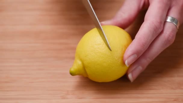 Woman cutting lemon in halves. Fresh citrus fruit on wooden cutting board - 映像、動画