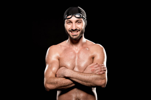 Gelukkig zwemmer staande met gekruiste armen geïsoleerd op zwart - Foto, afbeelding