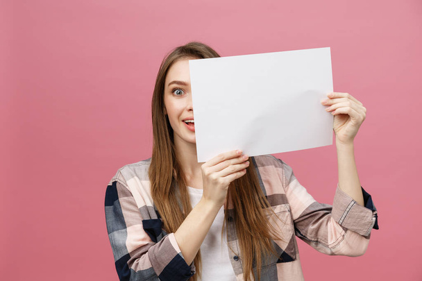 Young caucasian woman holding blank paper sheet over isolated background scared in shock with a surprise face, afraid and excited with fear expression - Photo, image