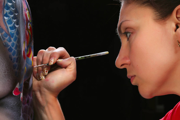 close-up portrait artist's, perform body painting koi fish on a black background studio - Photo, image