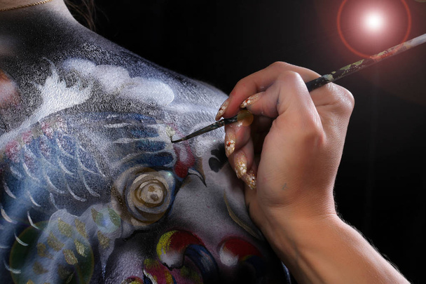 close-up artist's hand on the body art on a black background studio  - 写真・画像