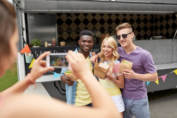 woman photographing friends eating at food truck - Photo, image