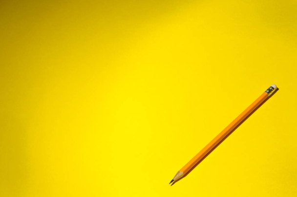 ハード シャドウと明るい黄色の背景に黄色の鉛筆を 1 つ。文房具。テキストのためのスペース - 写真・画像