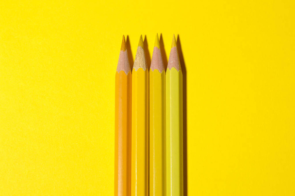 Τρεις κίτρινο μολύβια σε φωτεινό κίτρινο φόντο με ένα σκληρό σκιά. χαρτικά. το top view. χώρο για το κείμενο - Φωτογραφία, εικόνα