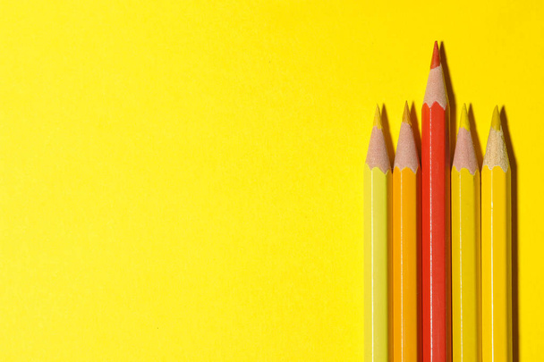 Κόκκινο μολύβι μεταξύ κίτρινοι σε φωτεινό κίτρινο φόντο. η έννοια της ατομικότητας. το top view. χώρο για το κείμενο - Φωτογραφία, εικόνα