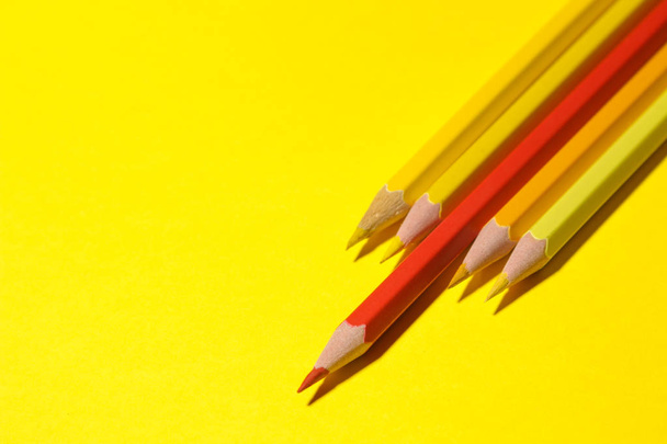 Red pencil among yellow ones on a bright yellow background. individuality concept - Photo, image