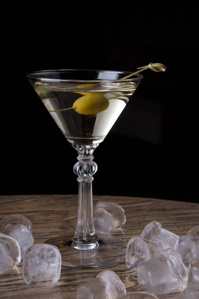 Martini glass with olive on a bar counter with ice cubes - Foto, Imagen