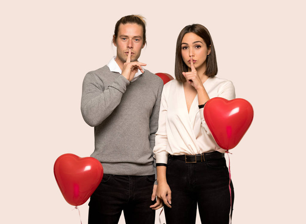 Пара в день Святого Валентина показывает знак молчания жест положить палец в рот на изолированном фоне
 - Фото, изображение
