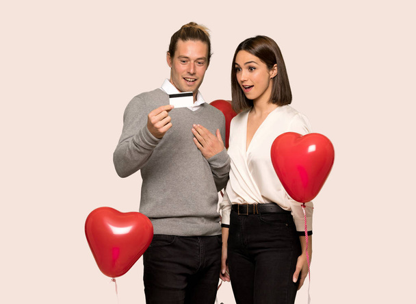 Couple in valentine day surprised and sending a message over isolated background - Фото, изображение