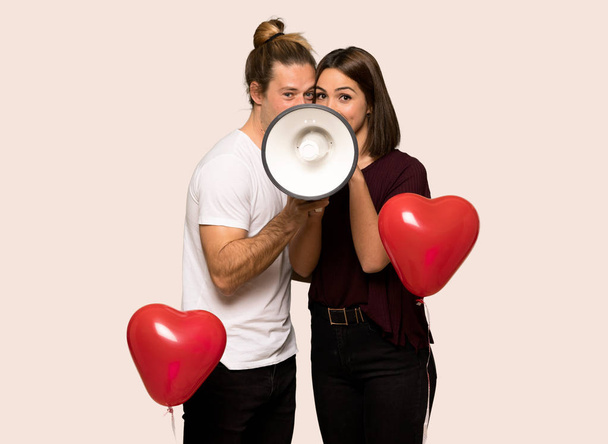 Paar am Valentinstag brüllt durch ein Megafon vor isoliertem Hintergrund - Foto, Bild