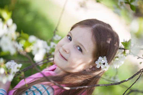 Cute girl in a blooming cherry tree garden - Valokuva, kuva