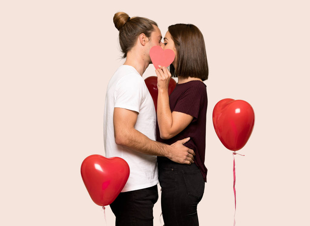 Pareja en día de San Valentín sosteniendo un símbolo del corazón y besándose sobre un fondo aislado
 - Foto, imagen