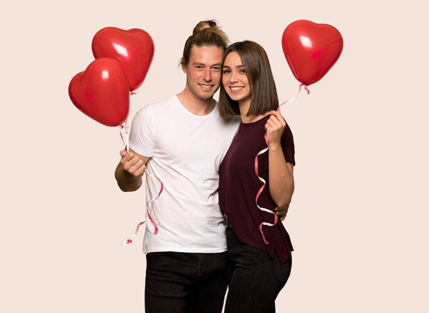 Ζευγάρι στην ημέρα του Αγίου Βαλεντίνου με μπαλόνια με σχήμα καρδιάς πέρα από το απομονωμένο υπόβαθρο - Φωτογραφία, εικόνα