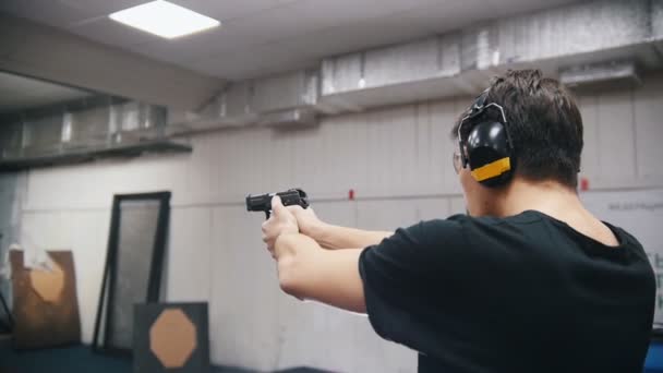 Galeria de tiro. Um jovem concentrado atirando com armas de fogo
 - Filmagem, Vídeo