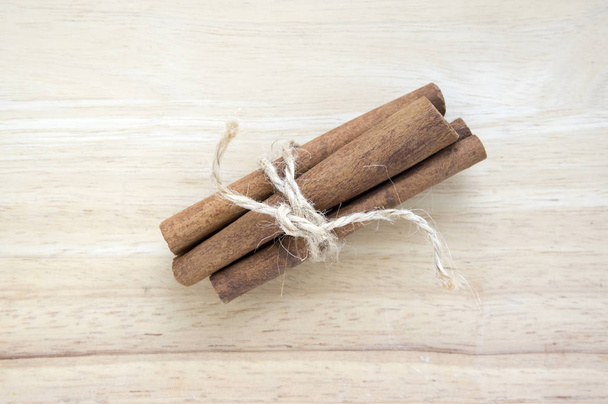 Fresh raw cinnamon sticks on wooden table tied with natural twine - Фото, изображение