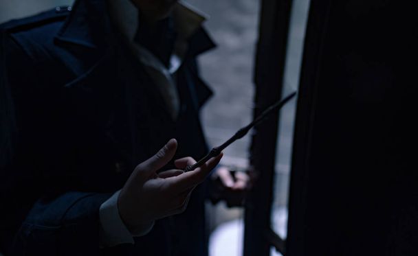 Молодой человек в образе черного фокусника с волшебной палочкой в руке. Крупный план
. - Фото, изображение