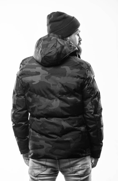 Man stand warm camouflage pattern jacket parka with hood isolated on white background. Hipster winter fashion. Guy wear hat and black winter jacket. Comfortable winter outfit. Winter stylish menswear - Fotoğraf, Görsel