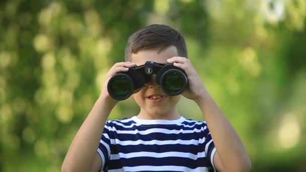 Niño pequeño caminando en el parque y mirando a través de los prismáticos
 - Imágenes, Vídeo