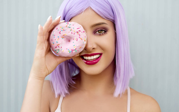 Portrait of beautiful young woman posing with doughnut - Foto, Imagen